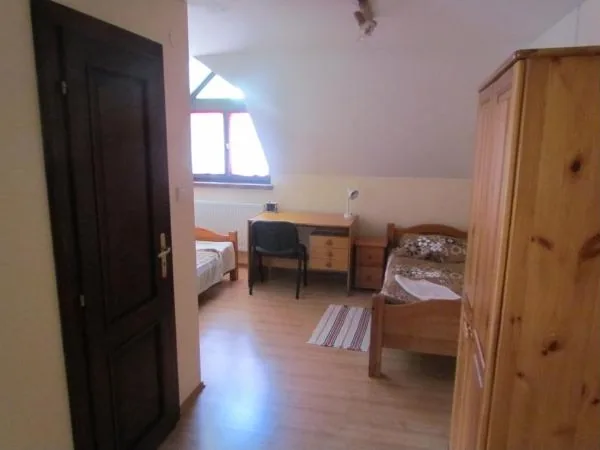 Podkrovná izba s dvoma posteľami, stolom a skriňou